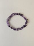 Amethyst crystal bracelet with polished purple chips on a cream background