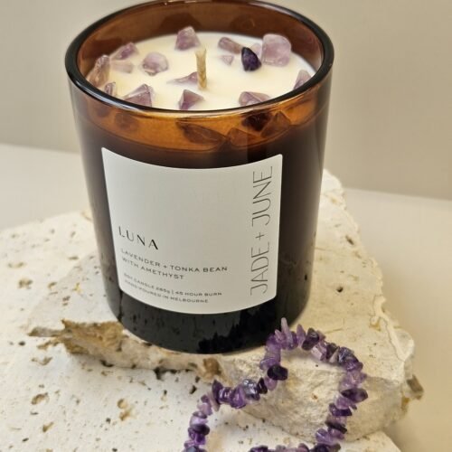Amethyst crystal bracelet beside the Luna candle on travertine, Amethyst chips set in the wax