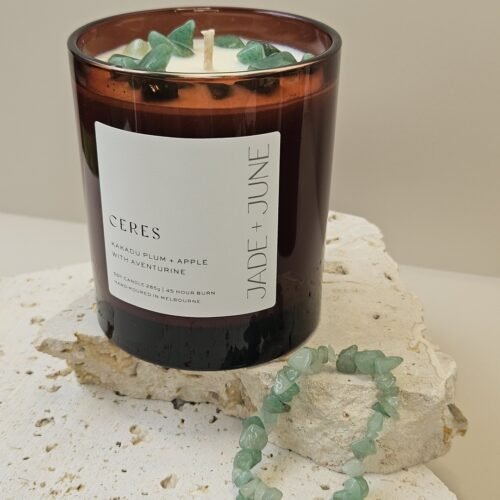 Green Aventurine crystal bracelet beside the Ceres candle on travertine, Green Aventurine chips set in the wax