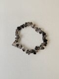Smoky Quartz crystal bracelet with polished grey chips on a cream background