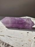 Amethyst double terminated point resting on a pale stone surface