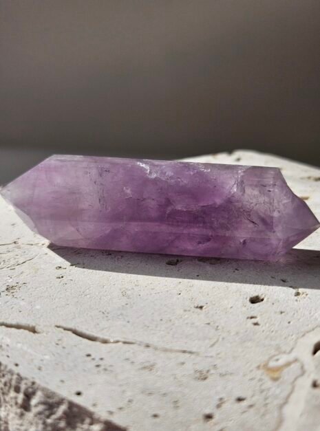 Amethyst Double Terminated 1 Amethyst double terminated point resting on a pale stone surface