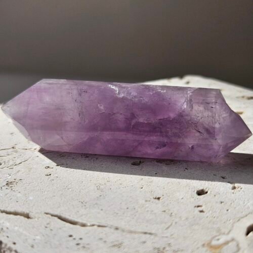 Amethyst Double Terminated 1 Amethyst double terminated point resting on a pale stone surface
