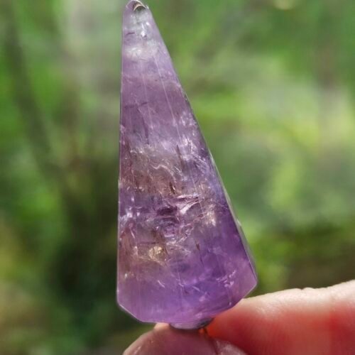 Amethyst Pendulum 5 Faceted Amethyst pendulum held up to the light, showing the purple through the stone