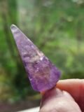 Faceted Amethyst pendulum held to the light, showing the facets catching the light
