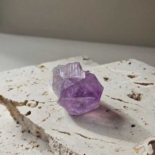 Rough Amethyst point on a pale stone slab