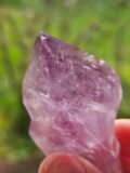 Close view of a rough Amethyst point, purple glowing through the crystal