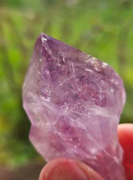 Amethyst Rough Point 4 Close view of a rough Amethyst point, purple glowing through the crystal