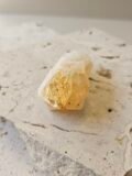 Small Citrine point on a cream surface, front facing