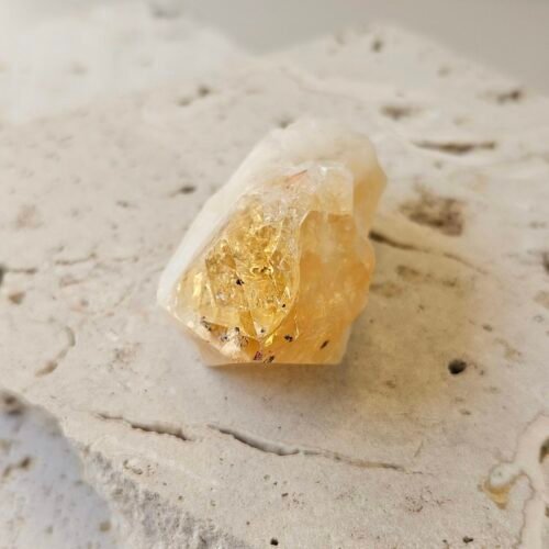 Small Citrine point on a cream surface, front facing