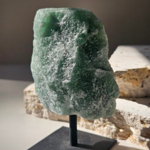 Rough Green Aventurine raised on a black stand, front facing
