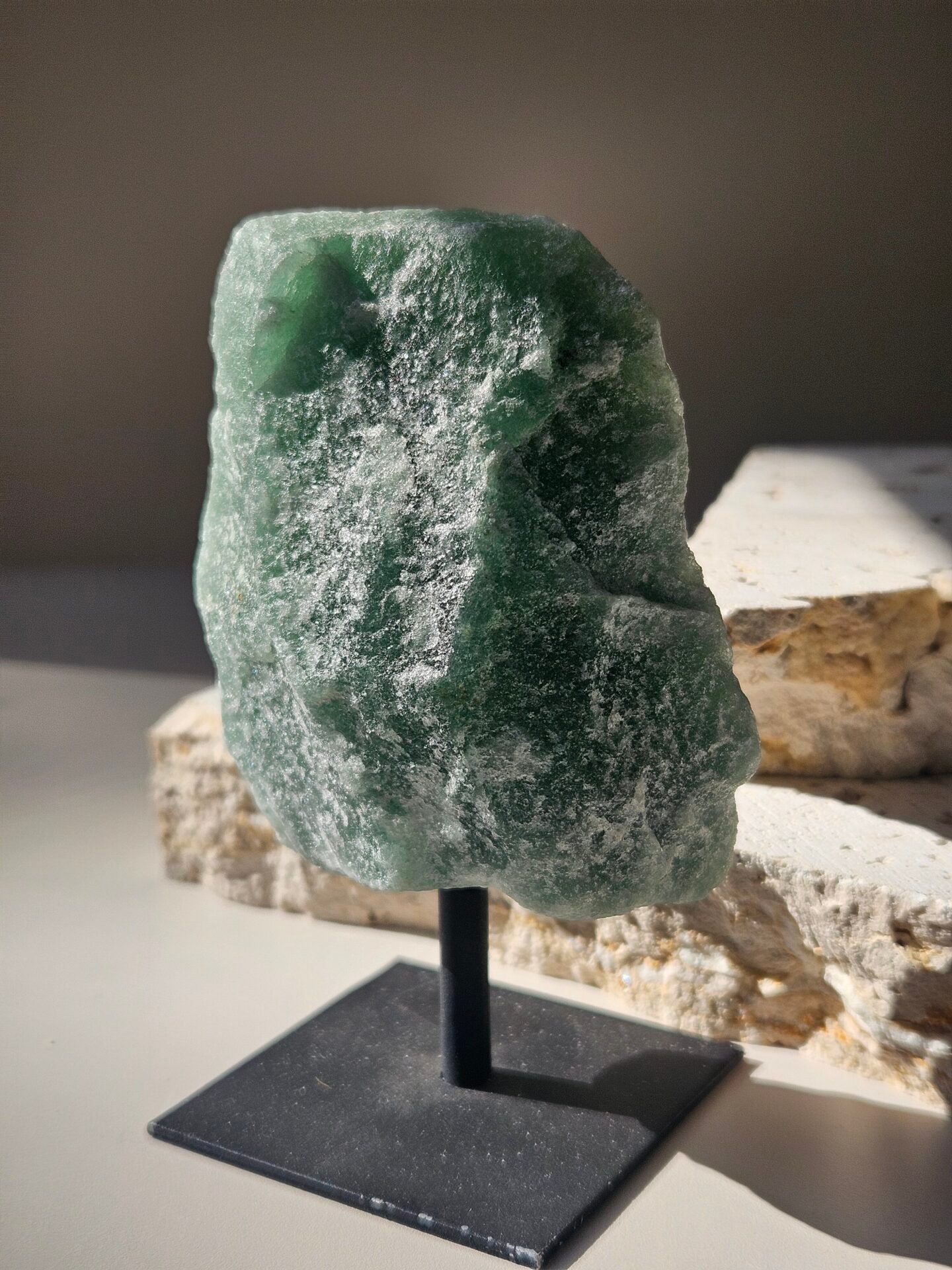 Green Aventurine Rough on Stand 4 Rough Green Aventurine raised on a black stand, front facing