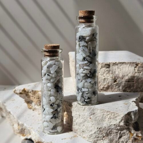 Two glass vials of Rainbow Moonstone chips standing side by side with cork lids