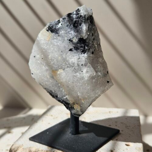 Rough Rainbow Moonstone on a black metal stand, front facing