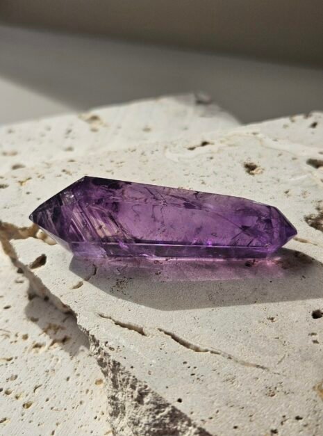 amethyst wand 2 Deep purple double-terminated Amethyst wand on a pale stone slab, rotated to another angle