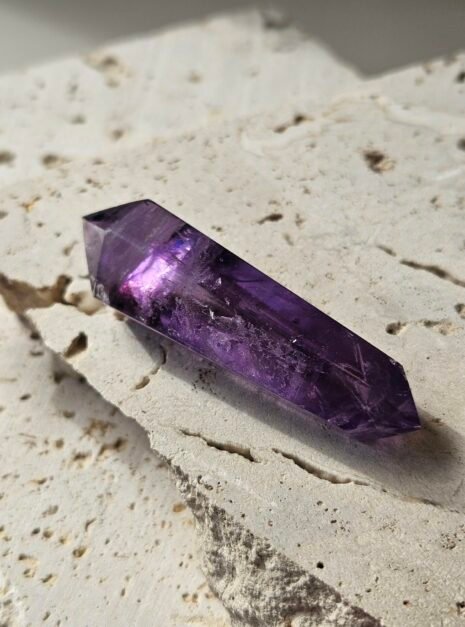 amethyst wand 4 Double-terminated Amethyst wand on a pale stone slab, showing both points