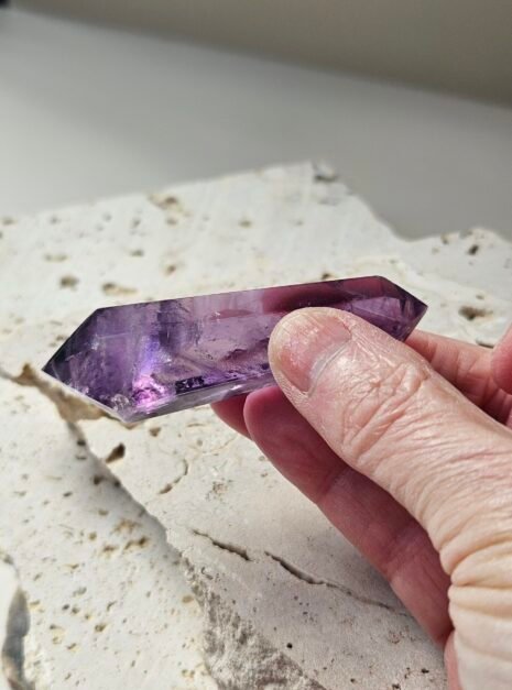 amethyst wand 6 Double-terminated Amethyst wand held lengthwise across the fingers